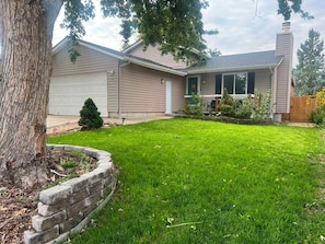 A residential house with a well-maintained lawn, a garage, and a chimney. - Home away from home (Aurora)