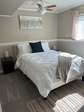 A bedroom with a bed, a ceiling fan, a window with curtains, and a wall-mounted artwork. - Home away from home (Aurora)