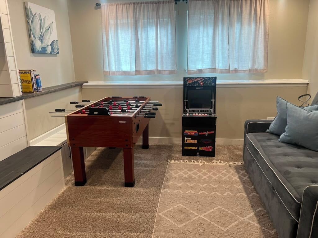 Una habitación con mesa de fútbol, sofá y televisión.