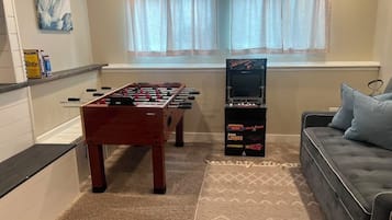 Una habitación con mesa de fútbol, sofá y televisión.