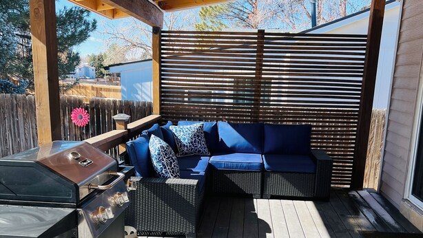 Un patio al aire libre con una parrilla, zona de estar y cubierta de madera.