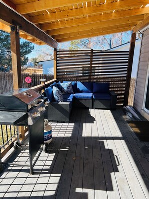 An outdoor patio with a grill, seating area, and wooden deck. - Home away from home (Aurora)