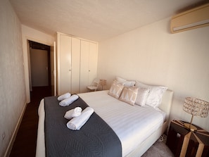 Een hotelkamer met een bed, een kledingkast, een stoel en een lamp.