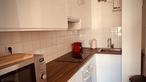 A modern kitchen with white cabinets, a microwave, a coffee maker, and a dishwasher. - The Pink Hippopotamus – Duplex with a terrace overlooking the M (Sète)