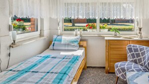 Un dormitorio con cama, escritorio, silla y ventana con vista a un jardín.