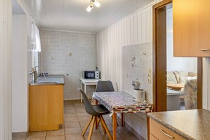 A compact kitchen with a sink, a microwave, a dining table with chairs, and a small countertop.