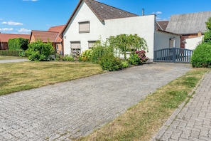 Een woonstraat met geplaveid pad, huizen met rode dakpannen en een hekpoort.
