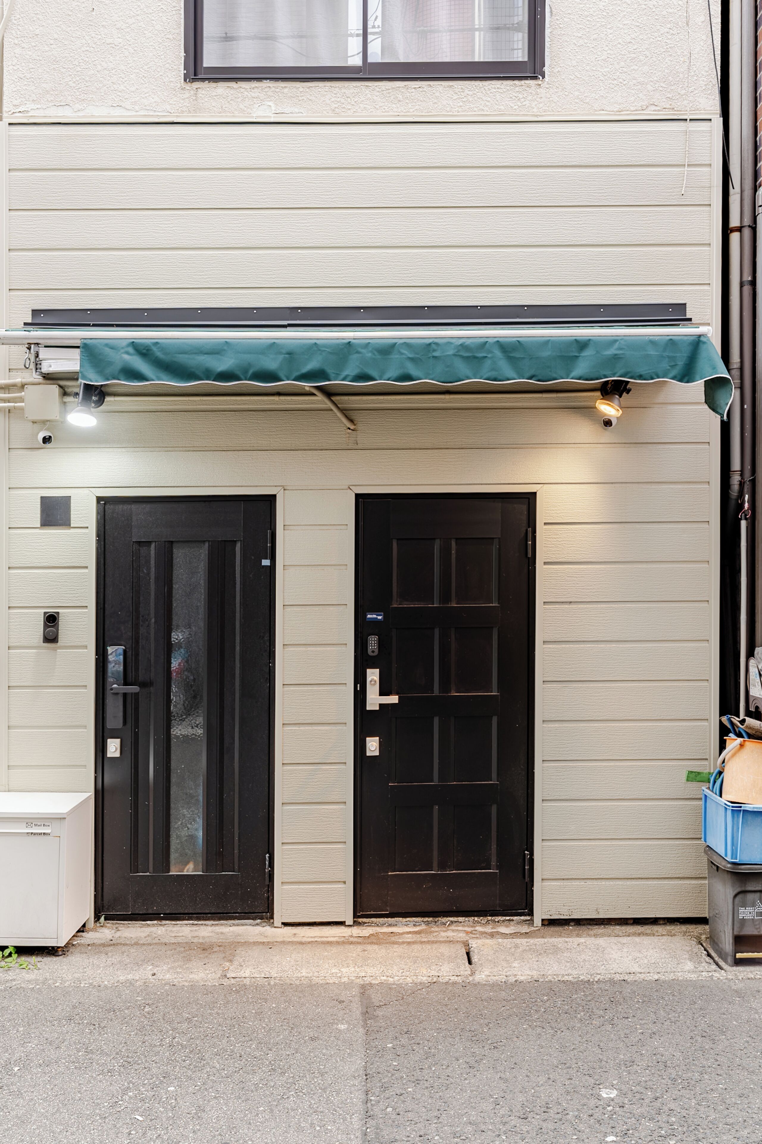 A building with two black doors, a green awning, and a security camera.