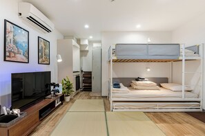 Habitació d'hotel petita amb un llit superposat, un televisió de pantalla plana, una cuineta senzilla i un quadre a la paret.