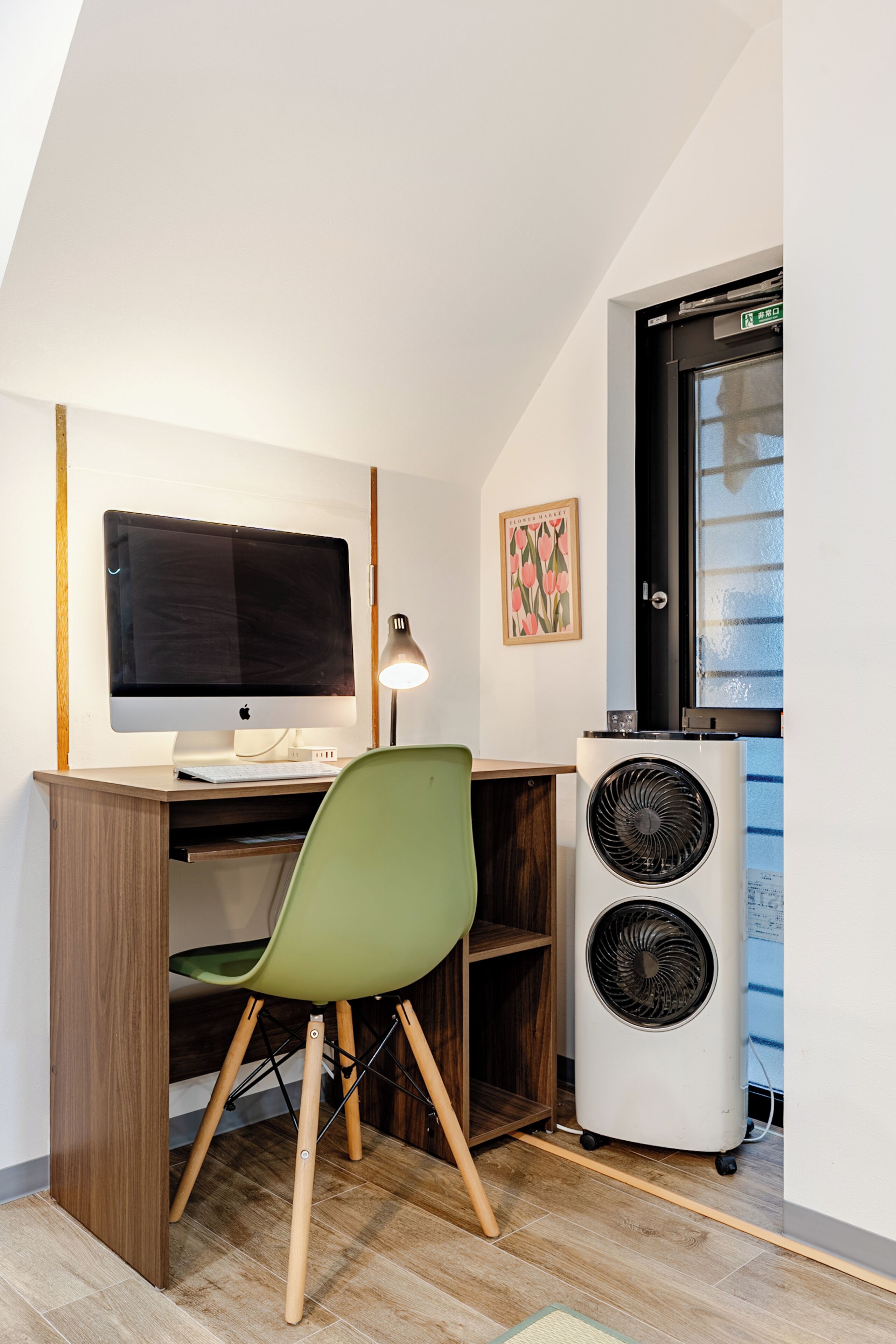 A room with a desk, a chair, a computer monitor, a lamp, and a large air conditioning unit.