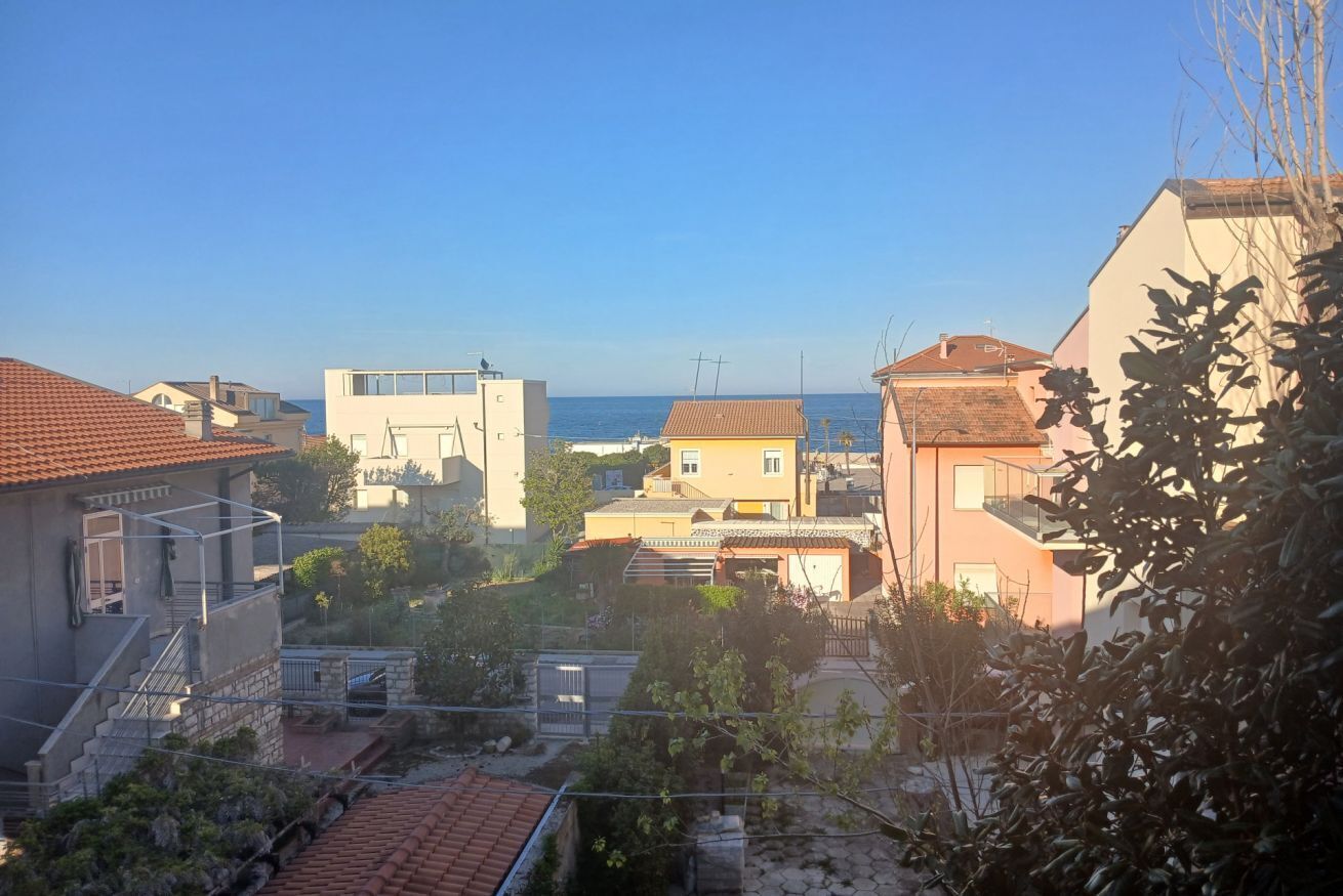 Ett bostadsområde med hus, en klar himmel och utsikt över havet.