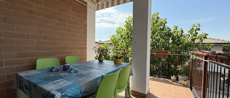 Un balcon avec une table et des chaises, un mur en briques et une vue sur la verdure et les bâtiments.