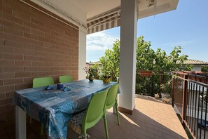 Ein Balkon mit Tisch und Stühlen, eine Backsteinmauer und Blick auf Grünflächen sowie Gebäude.