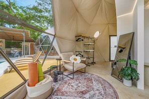 A tented room with a large window, a chair, a hanging shelf, and a mirror. - Private Domes with a Pool Near Playa Grande (Matapalo)
