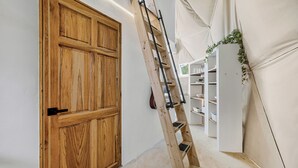 Eine Holztür, eine Holzleiter und weiße Regale in einem Raum.