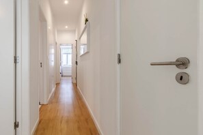 A hallway with wooden flooring, white walls, and a door with a silver handle. - Garden Terrace - Lisbon City Retreat (Lisboa)