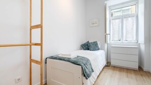 Et soveværelse med seng, et vindue, en garderobe og en stige.