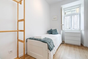 Een slaapkamer met een bed, een raam, een kast en een ladder.