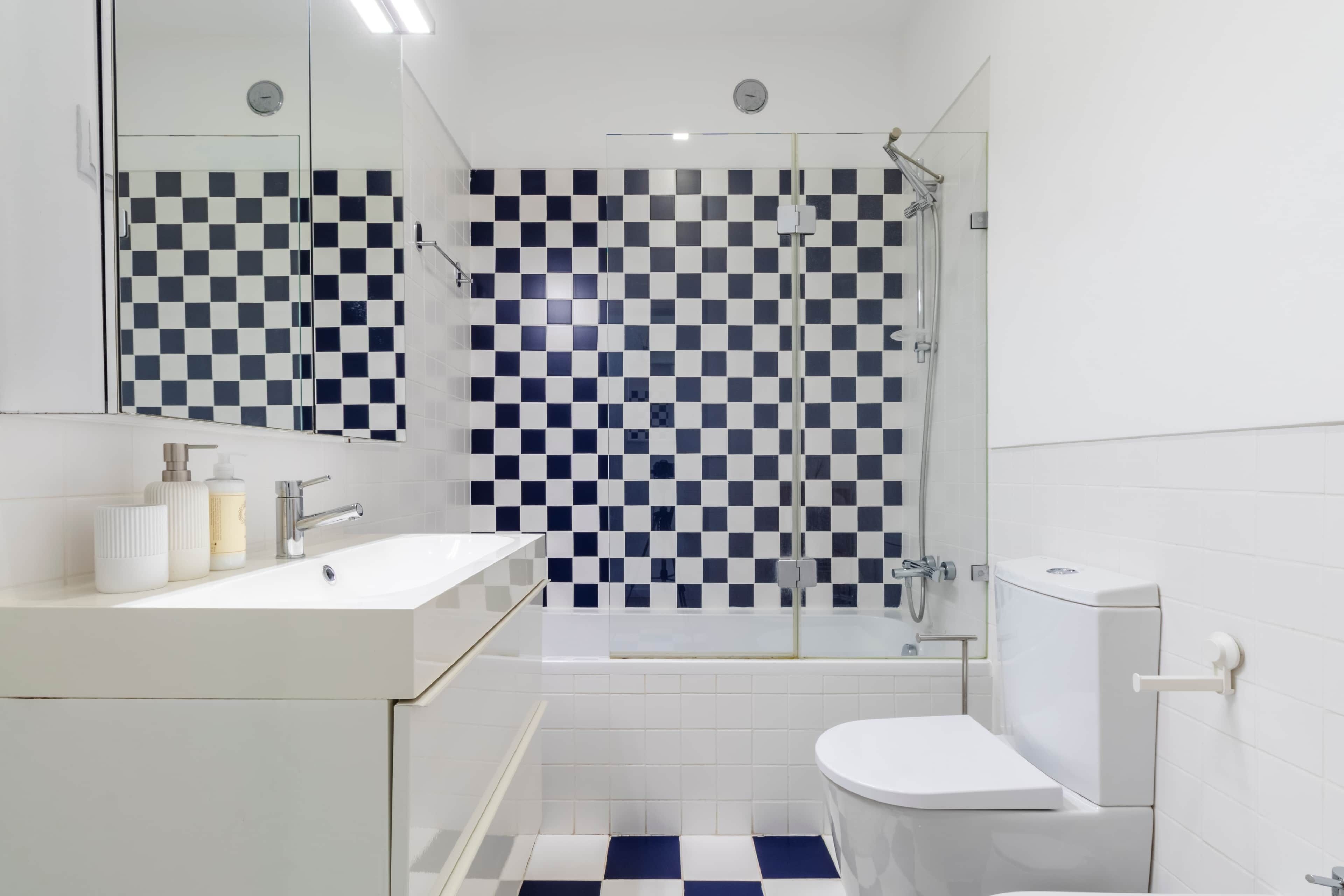 Ein modernes Badezimmer mit Wandgestaltung aus Schachbrettfliesen, einem weißen Waschbecken und einer Toilette.