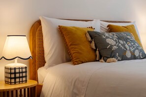 A neatly made bed with white bedding, a lamp with a checkered base, and two pillows with tassels. - Garden Terrace - Lisbon City Retreat (Lisboa)