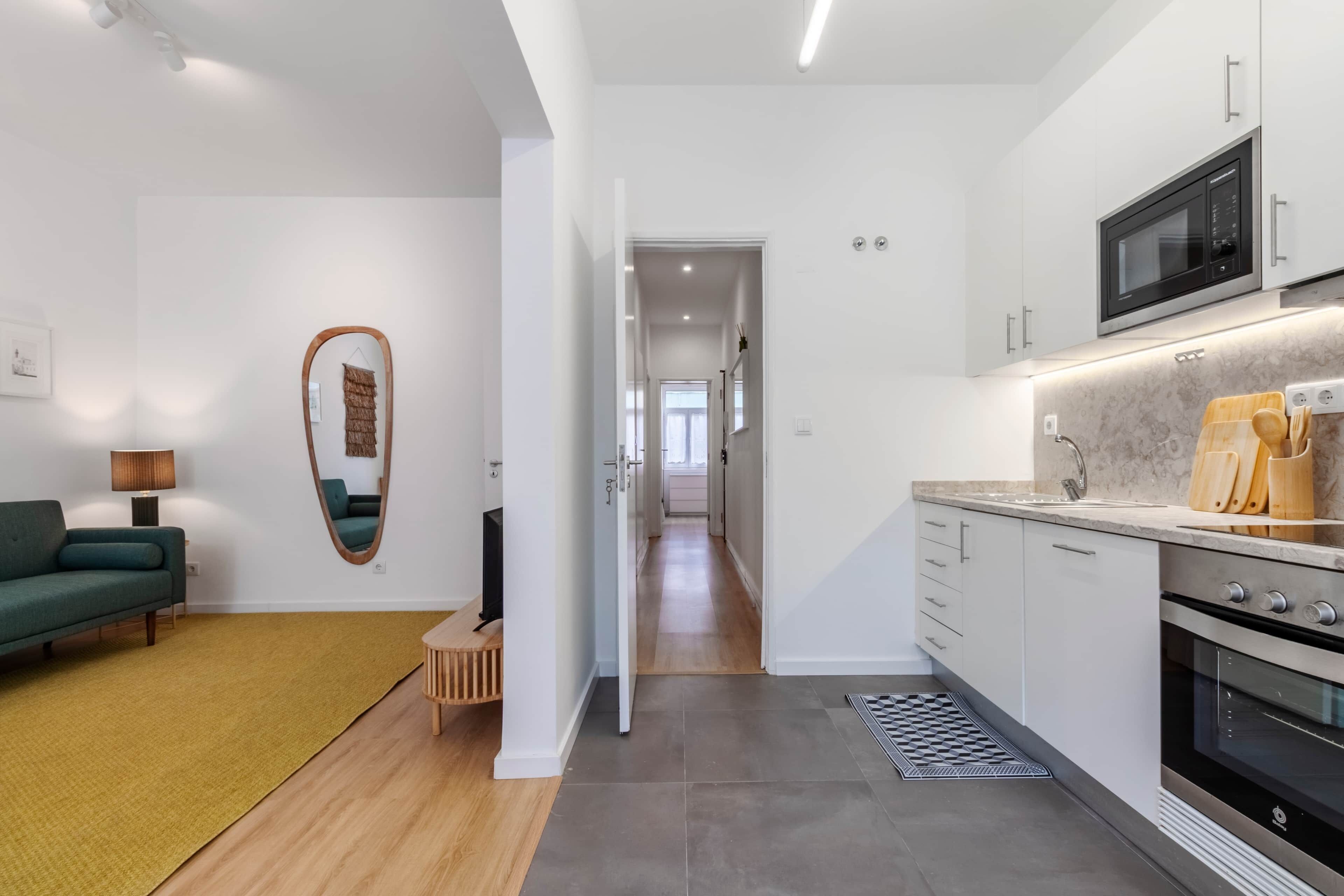 A modern kitchen with a built-in microwave, oven, and a countertop with a sink.