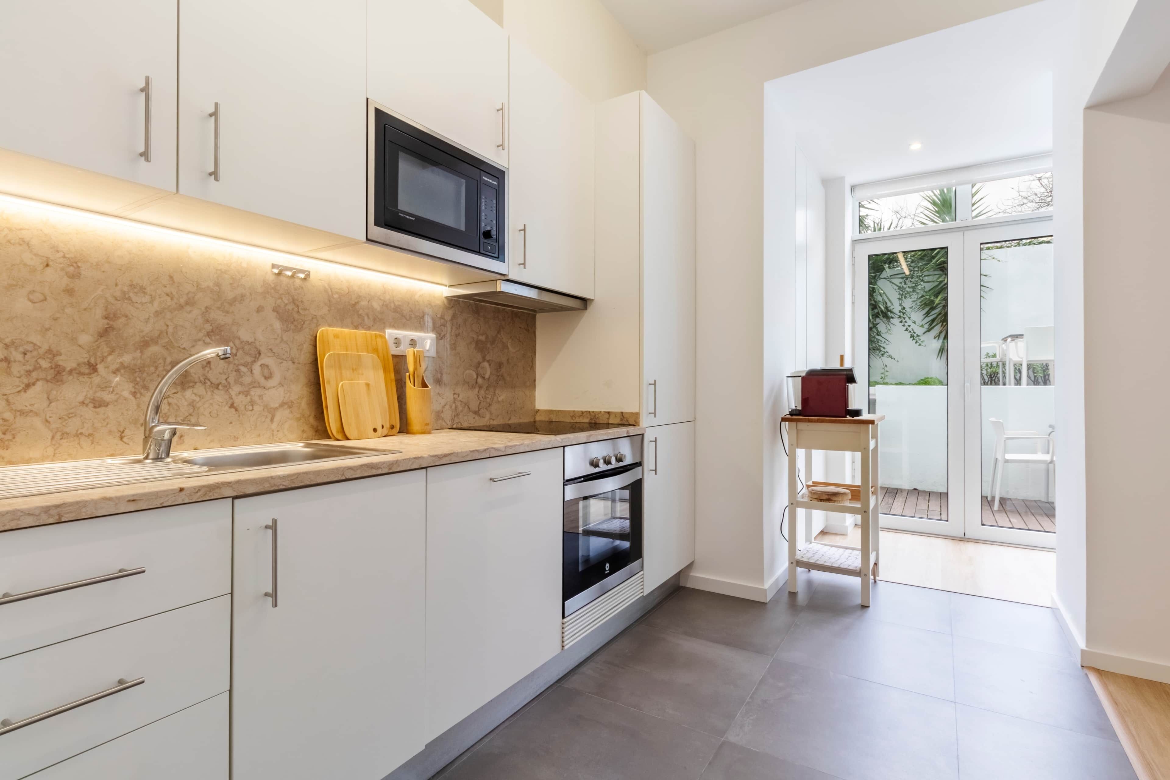 A modern kitchen with white cabinetry, a built-in microwave, and a stainless steel oven.