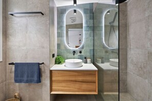 A modern bathroom with a wooden vanity, a round mirror, and a towel rack. - Cosy Coastal Retreat (Torquay)