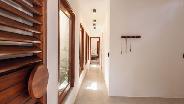 Un pasillo con listones de madera a la izquierda, un banco y un perchero en la pared.