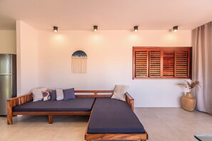 Ein modernes Wohnzimmer mit einer Sofagarnitur, einer Holzbank, einer Wanddekoration und einem Fenster mit Rollläden.