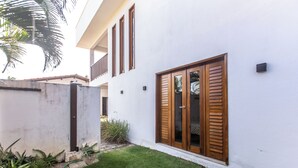 Un edificio moderno con fachada blanca, grandes contraventanas de madera y un césped cuidado.