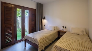 Un dormitorio con dos camas, una mesita de noche, una lámpara y un ventanal corredero que da a un jardín.