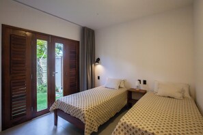 A bedroom with two beds, a nightstand, a lamp, and a sliding glass door leading to a garden. - Guesthouse Flamingo with 2 bedrooms and garden in the heart of Cumbuco (Caucaia)