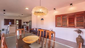 Un comedor moderno con una mesa de vidrio, sillas de madera y una lámpara de techo trenzada.
