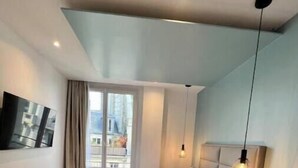 Un dormitorio con cama, mesita de noche, lámpara colgante y ventana con cortinas.