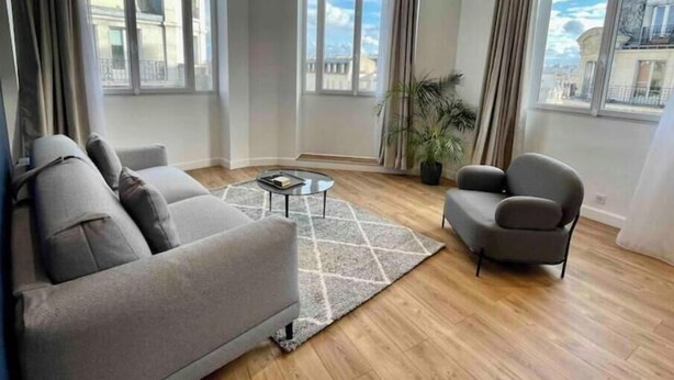 Una sala de estar moderna con un sofá, un sillón, una mesa de centro y una planta en maceta.