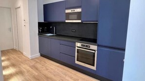 Una cocina moderna con armarios azul oscuro, un horno de acero inoxidable y una encimera negra.