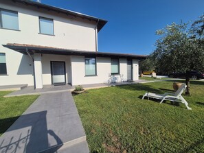 A modern two-story house with a flat roof, large windows, and a well-maintained lawn.