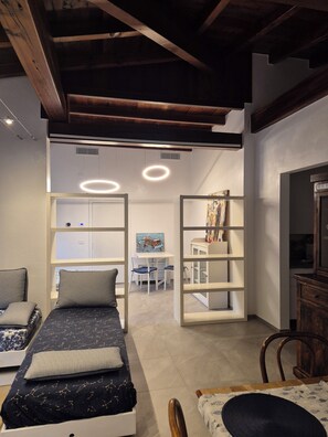 A bedroom with a bed, a desk, and a chair. There are bookshelves and a painting on the wall.