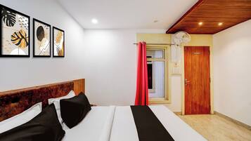Ein Schlafzimmer mit einem Bett, einem Holzkopfende, einem Deckenventilator, einer Tür und Wandbildern.