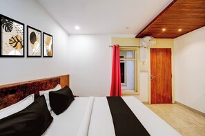 A bedroom with a bed, a wooden headboard, a ceiling fan, a door, and wall art. - Rani Kamlapati Railway Station (Bhopal)