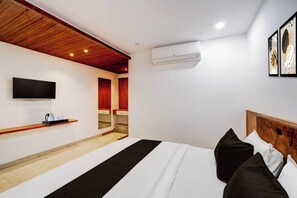 A modern bedroom with a bed, a mounted TV, and an air conditioning unit.