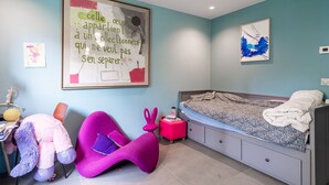 Un dormitorio con cama, escritorio, silla y una pared con una cita enmarcada.