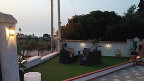 A rooftop terrace with a seating area, artificial grass, and a decorative wall. - Villa ROSALIA with a Jacuzzi, Barbecue, and Sunset View (Tonnara di Bonagia)