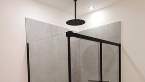A modern shower enclosure with a glass door, a black frame, and a ceiling-mounted showerhead. - Villa ROSALIA with a Jacuzzi, Barbecue, and Sunset View (Tonnara di Bonagia)
