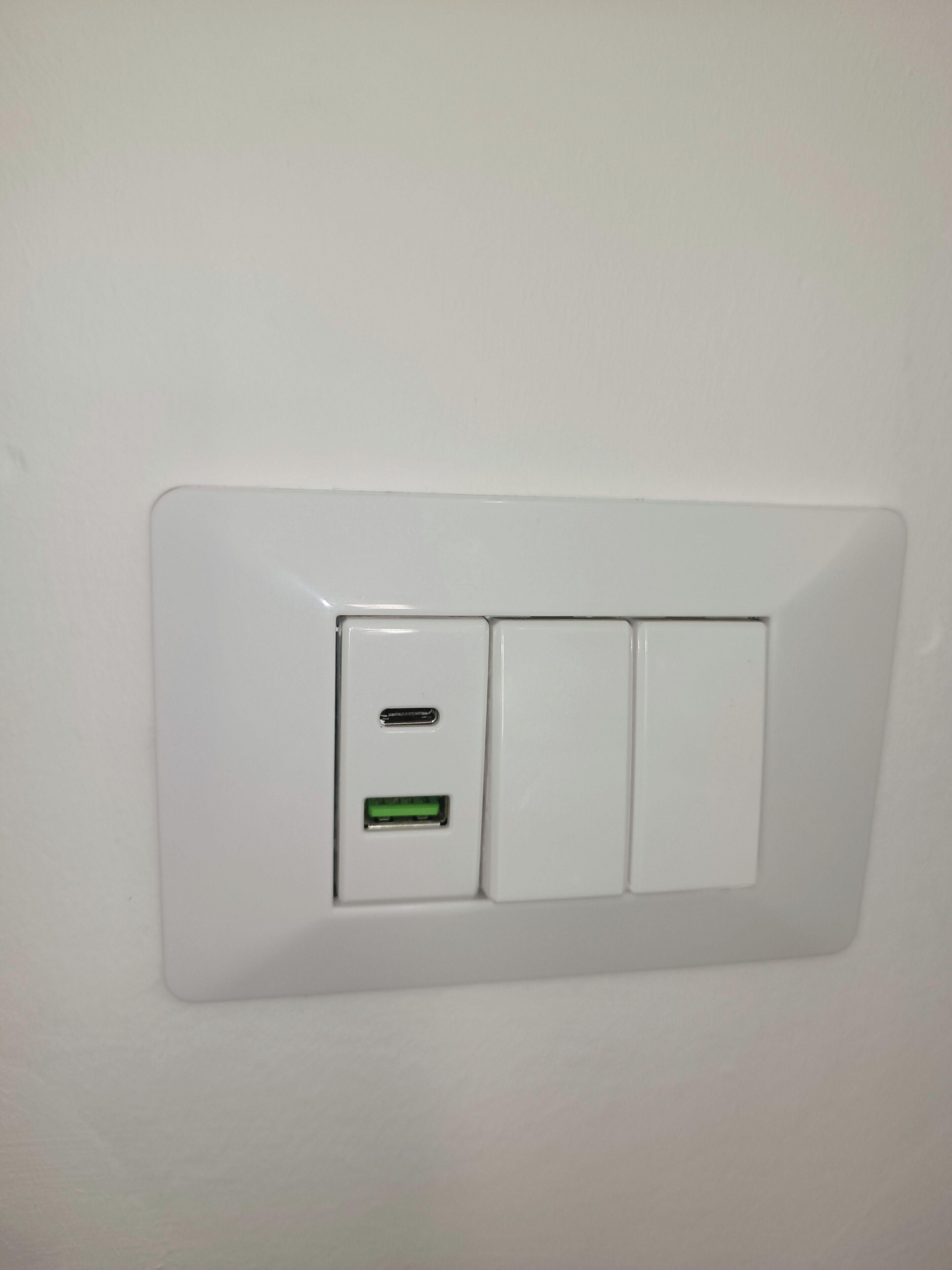 Interruptor fixado na parede branco, com duas portas USB e uma luz indicadora verde.