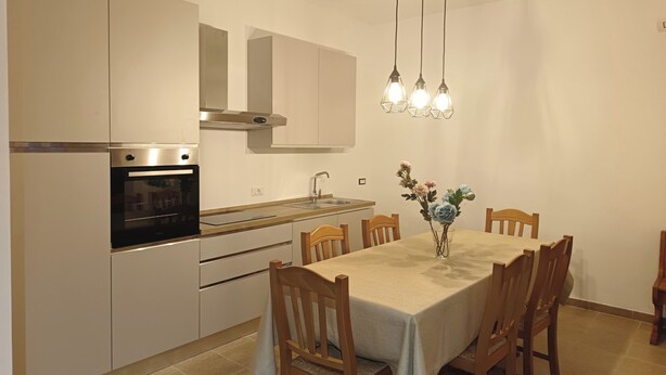 A modern kitchen with built-in appliances, a dining table with chairs, and pendant lighting. - Villa ROSALIA with a Jacuzzi, Barbecue, and Sunset View (Tonnara di Bonagia)