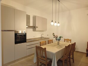 Uma cozinha moderna com eletrodomésticos de aço inoxidável, uma mesa de jantar com cadeiras e iluminação pendente.