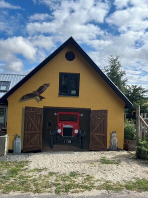 En bygning med gul facade, en rød bil og en statue af en ulv.