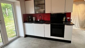 Eine moderne Küche mit weißen Schränken, einer schwarzen Arbeitsplatte und einer roten Spritzschutzwand.