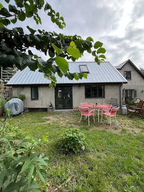A residential property with a metal roof, a front door, and a patio with outdoor furniture.